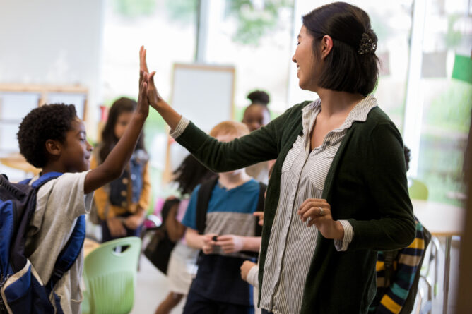 A photo showing a teacher giving her student a high five.