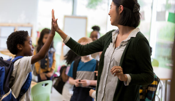 A photo showing a teacher giving her student a high five.