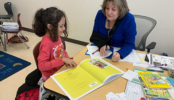 Photo of a tutor helping a student with reading skills.