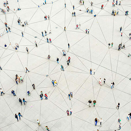An aerial photo of a crowd of people, with illustrated lines superimposed connecting them in interconnected networks.